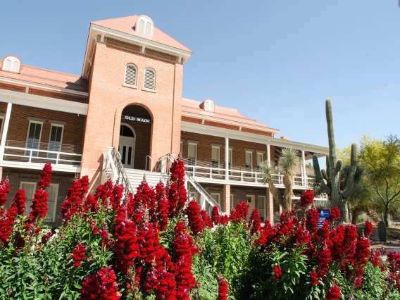 old main with red flowers in front of building