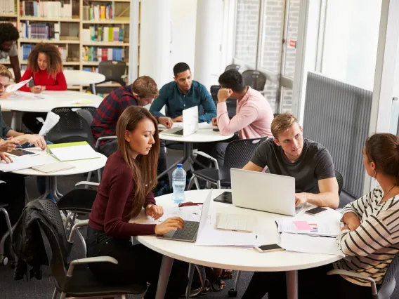 groups of students sitting around tables collaborating and studying