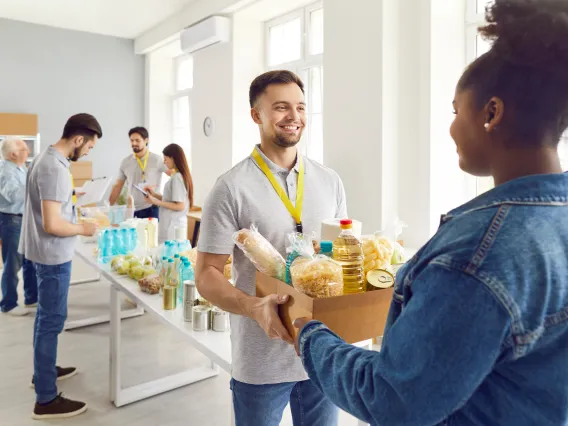 man handing woman a box of groceries at public pantry