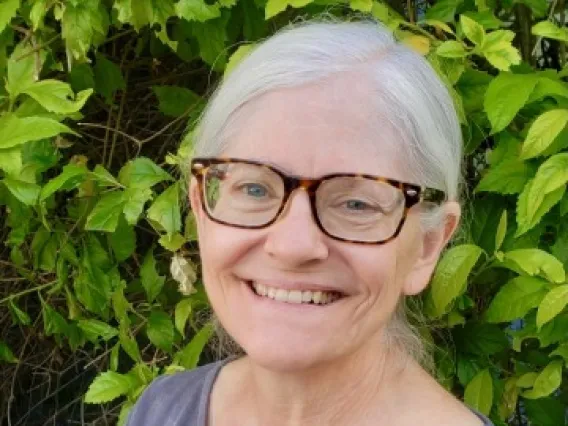 woman smiling at camera in front of plant