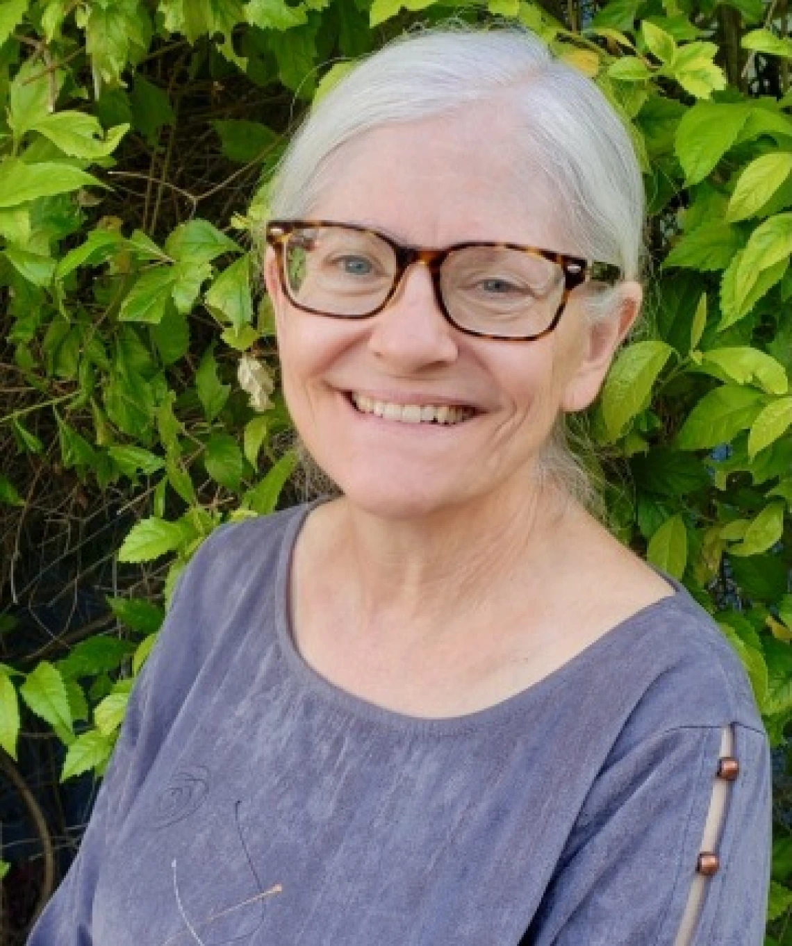 woman smiling at camera in front of plant